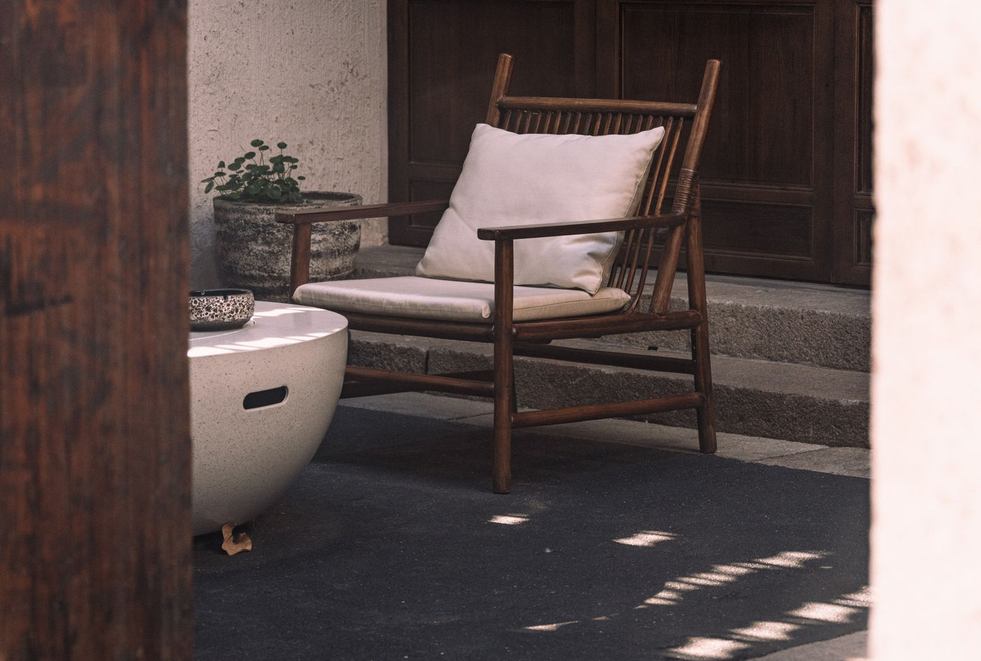 A serene outdoor patio arrangement featuring a wooden chair and a round table under natural light.