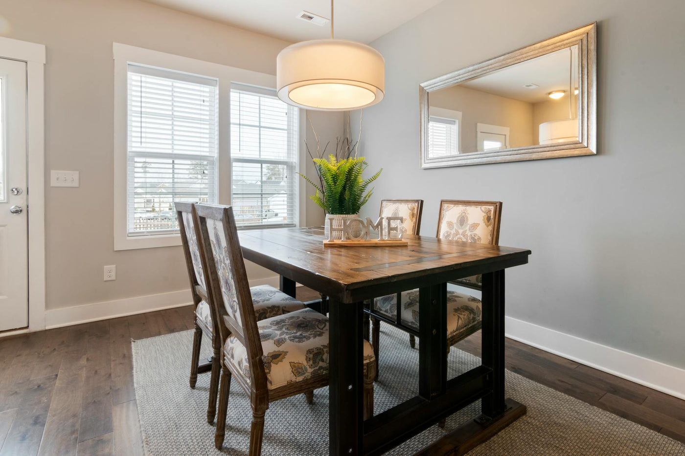 Bright and airy dining room featuring wooden table, floral chairs, and modern lighting.