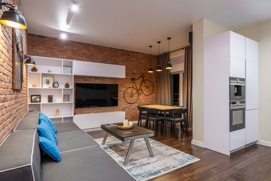 Dining room interior with tables and couch against built in appliances on wooden floor in light house
