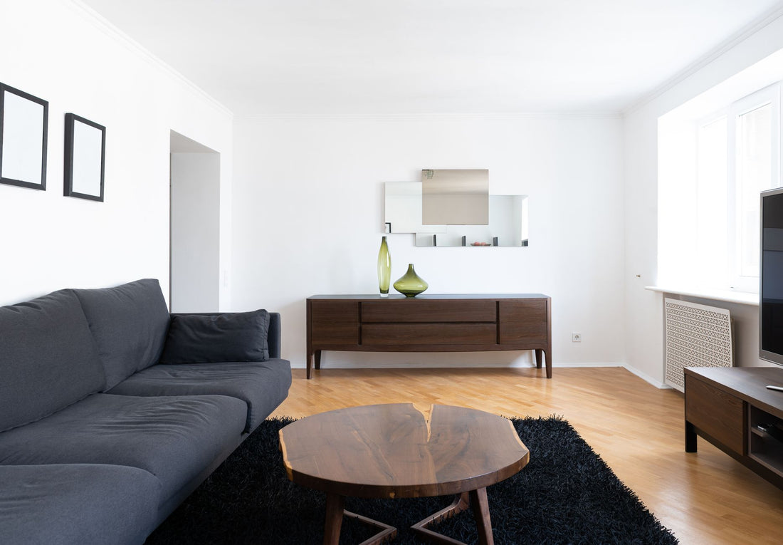 Interior of modern light home with couch near wooden table on carpet near cabinets with vases and TV