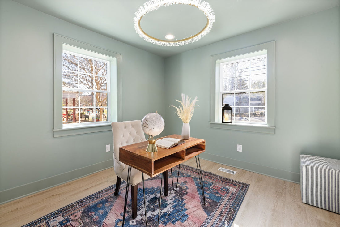 A serene home office with chic decor, featuring a wooden desk, tufted chair, and large windows for natural light.