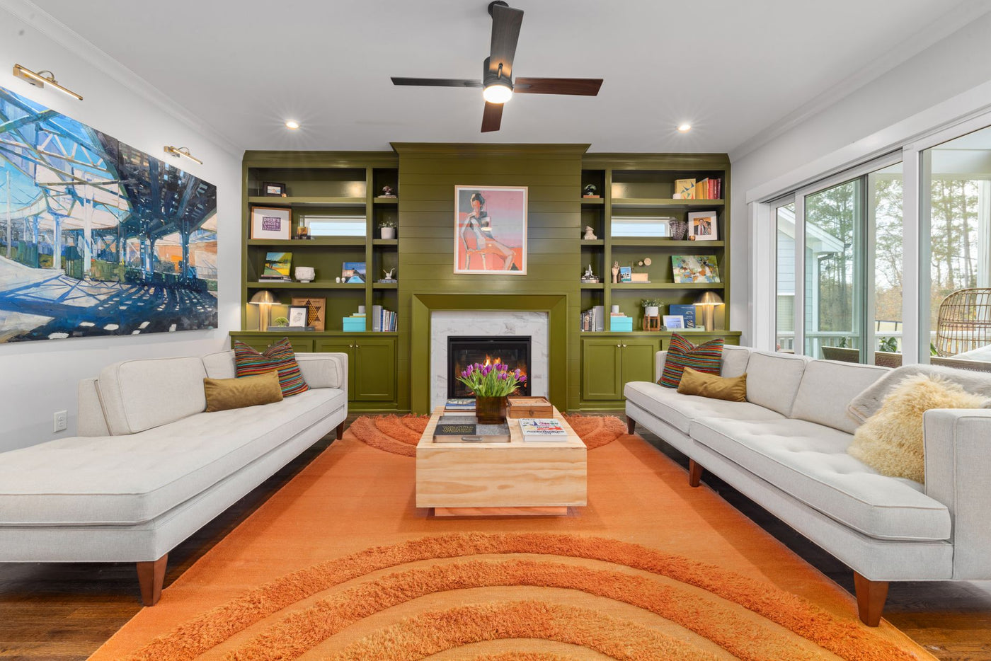 Elegant living room featuring green bookshelves, cozy sofas, and a vibrant orange rug.