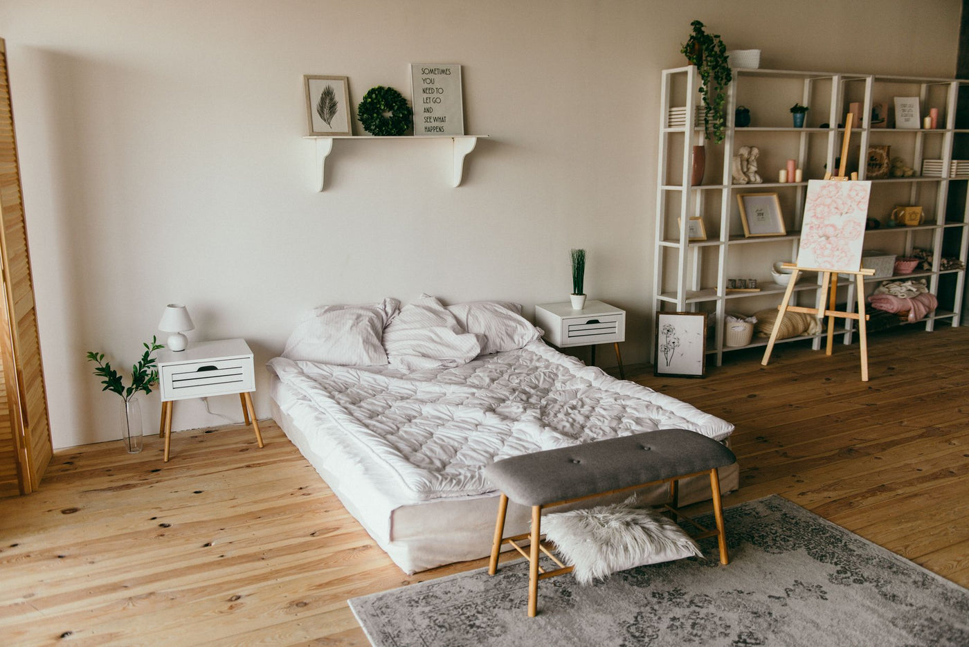 Spacious modern bedroom with minimalist decor, featuring a low bed, wooden floors, and shelf storage.