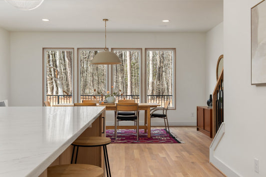 Bright dining room with wooden furniture and forest view through large windows, ideal for seasonal decor.
