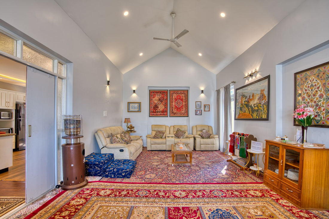 Spacious living room in Kashmir featuring plush sofas and colorful traditional carpets.