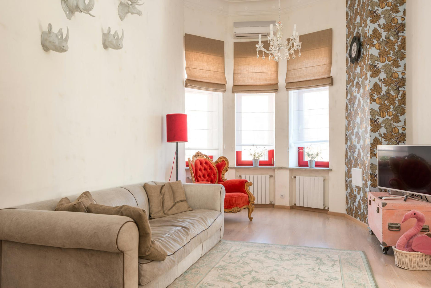 Stylish living room with a plush sofa, red armchair, and ornate decor elements.