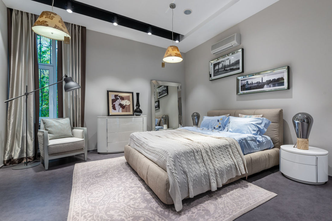 Interior of modern bedroom with comfortable bed and armchair pictures on wall hanging lamps and carpet on floor and beige silk curtains