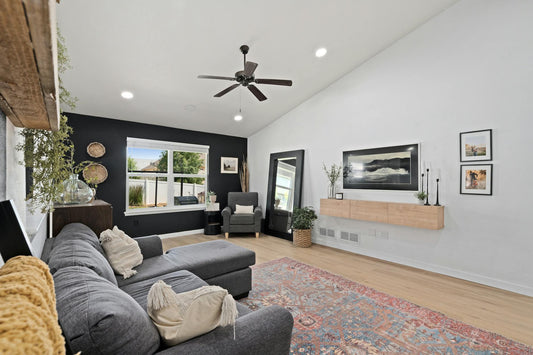 A stylish and cozy modern living room featuring a sectional couch, decorative elements, and natural light through large windows.