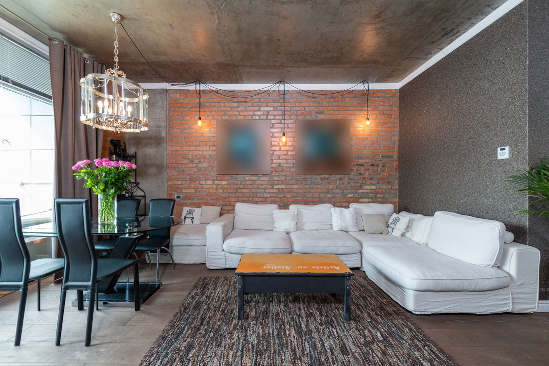 Stylish living room featuring industrial design with brick wall, white sofa, and chic chandelier.