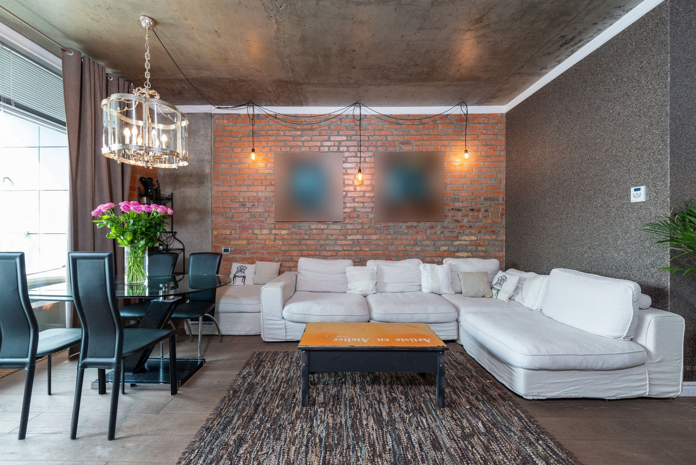 Stylish living room featuring industrial design with brick wall, white sofa, and chic chandelier.
