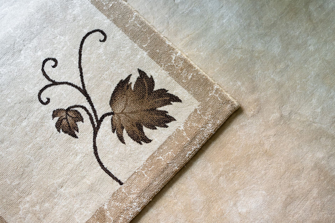 A close-up of a beige carpet with an elegant leaf design, showcasing intricate detail and texture.