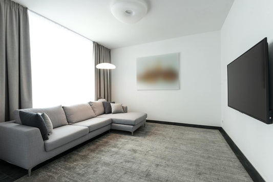Spacious modern living room with L-shaped grey sofa and flat-screen TV in a minimalist design.