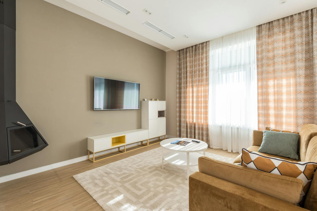 Bright modern living room with a sofa, coffee table, and large window curtains.