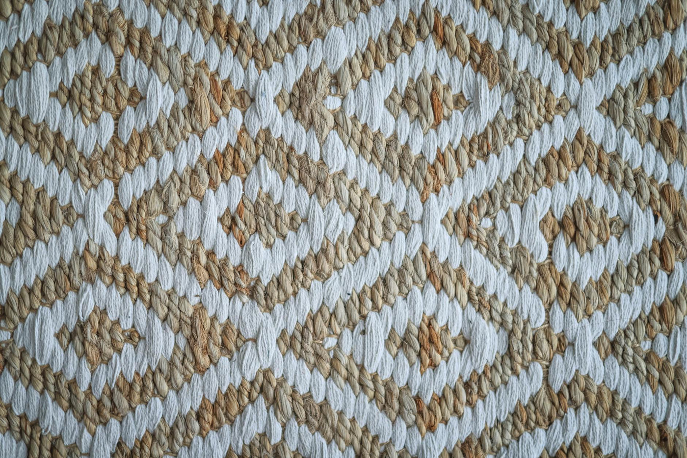 Detailed view of a woven rug with a beige and white geometric pattern.