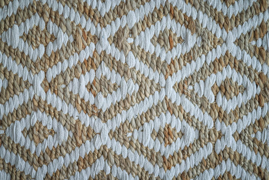 Detailed view of a woven rug with a beige and white geometric pattern.