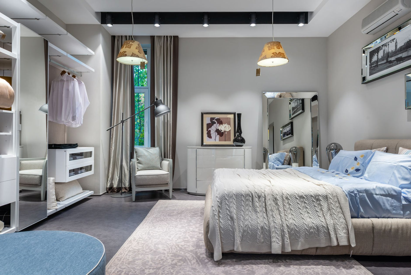 Comfortable bedroom with knitted coverlet and cushions built in spacious wardrobe armchair chest and mirror and hanging lamps