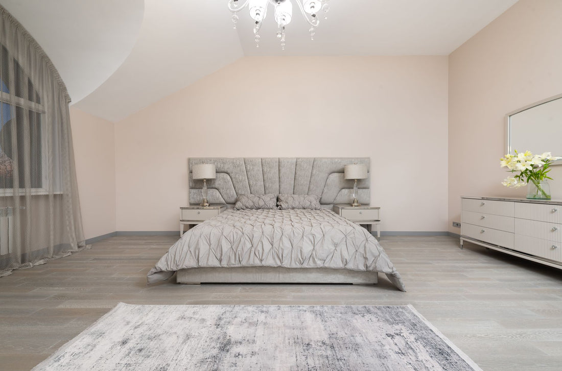 Interior of modern spacious bedroom with comfortable bed with gray blanket placed between window and cupboard with flowers and mirror