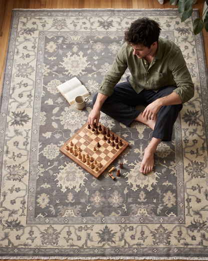 Artisan Emma Pewter Beige Style Shot — Pewter and beige floral rug beneath a man playing chess.