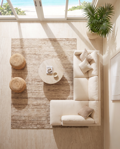 Artisan Natural Weave Ivory Living Room Overhead Shot — Overhead view of an ivory rug with subtle linear texture, cream seating, and woven ottomans.