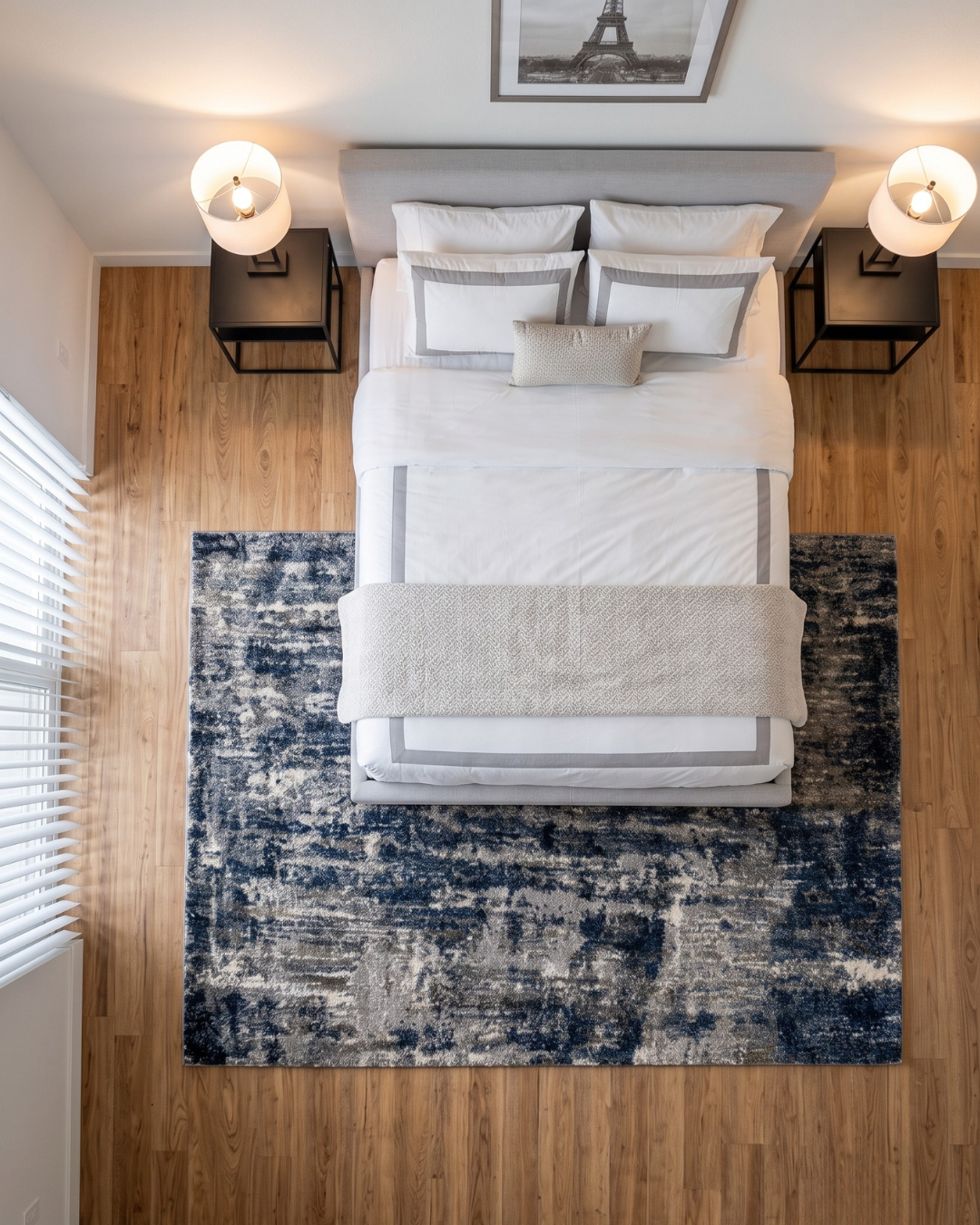 Oriental Weavers Aspen 2061L Grey Blue Bedroom Overhead Shot — Grey and blue abstract rug beneath a modern upholstered bed.