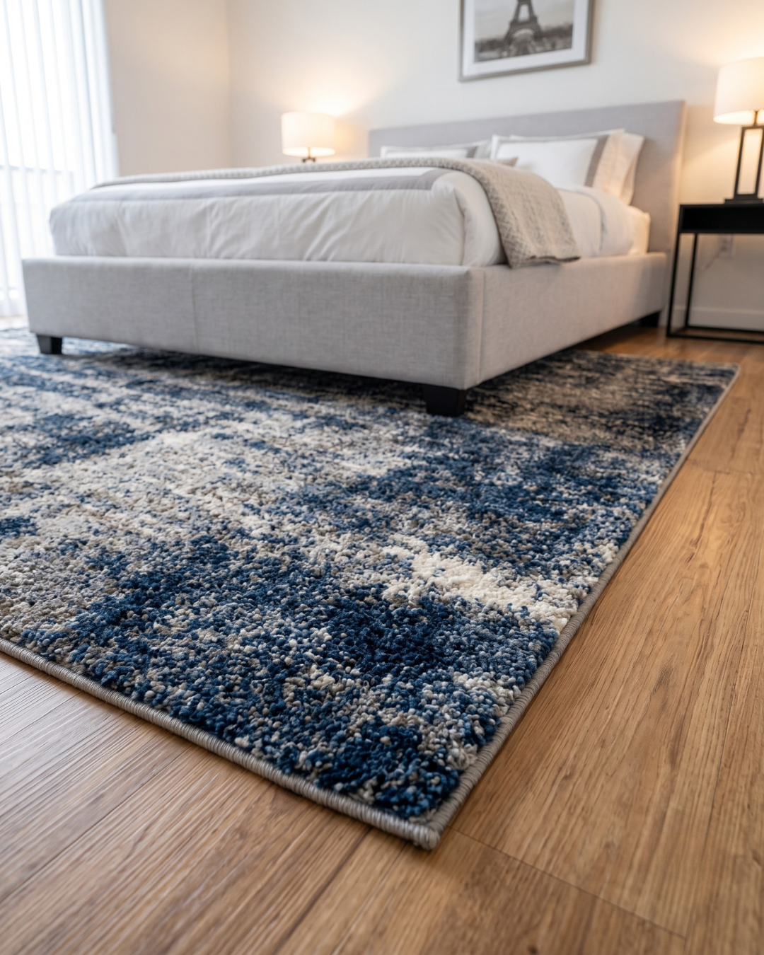 Oriental Weavers Aspen 2061L Grey Blue Corner Shot — Textured grey and blue abstract rug beneath a modern upholstered bed.