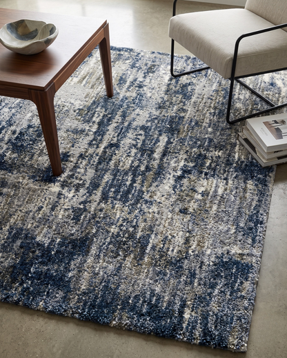 Oriental Weavers Aspen 2061L Grey Blue Style Shot — Grey and blue abstract rug styled with a modern wood coffee table and accent chair.